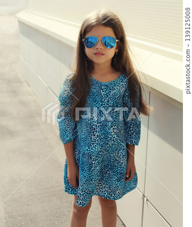 Beautiful little girl child wearing blue dress on city street Beautiful little girl child wearing blue dress on city street 139125008