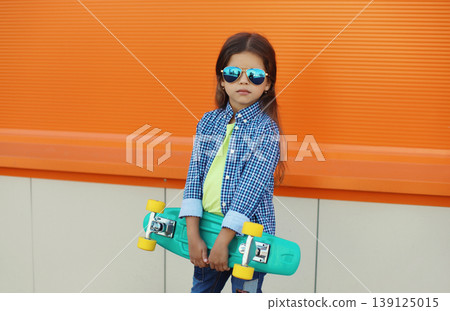 Stylish girl child with skateboard posing in the city Stylish girl child with skateboard posing in the city 139125015