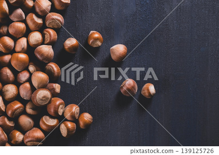 Raw hazelnuts in a stone mortar against a dark background. Raw hazelnuts in a stone mortar against a dark background. 139125726