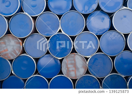 Blue and silver metal barrels arranged in rows. Stack of used metal barrels in industrial area. Blue and silver metal barrels arranged in rows. Stack of used metal barrels in industrial area. 139125873