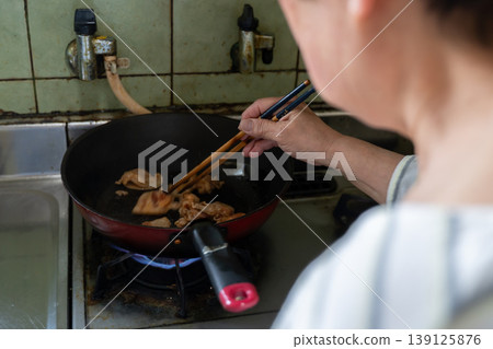 A woman stir-frying meat 139125876