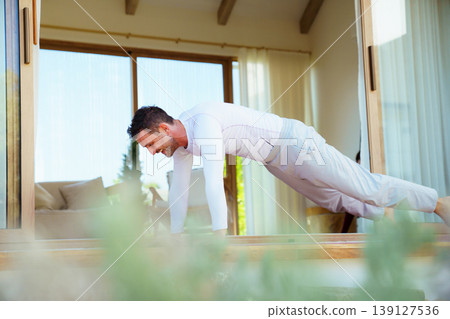Healthy man practicing yoga plank pose on sunny balcony at home Healthy man practicing yoga plank pose on sunny balcony at home 139127536