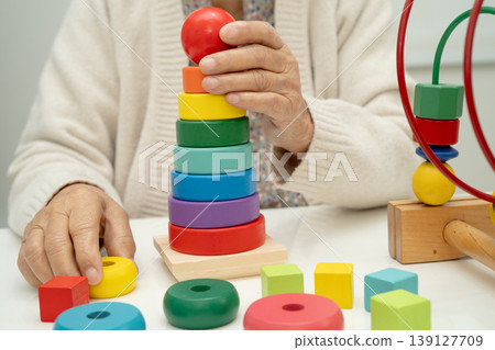 Asian elderly woman playing enhancing skill board game. Asian elderly woman playing enhancing skill board game. 139127709