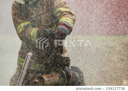 Firefighter turning water valve during outdoor training session 139127736