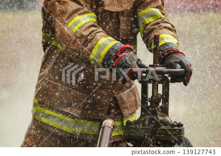 Firefighter turning water valve during outdoor training session Firefighter turning water valve during outdoor training session 139127743