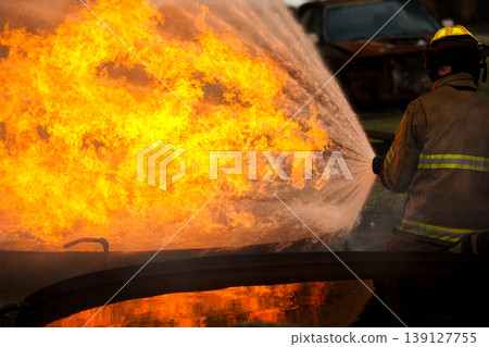 Professional fire fighters extinguishing intense fire with water hose Professional fire fighters extinguishing intense fire with water hose 139127755