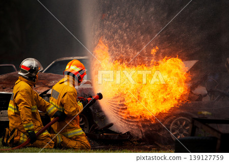 Firefighters putting out intense car fire with water spray Firefighters putting out intense car fire with water spray 139127759