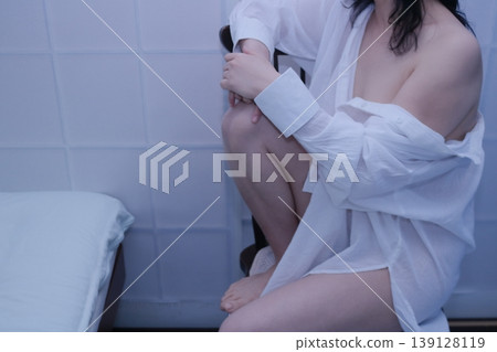 A woman wearing a white shirt sits in a chair. 139128119