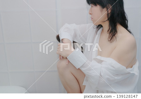 一位身穿白襯衫的女子坐在椅子上。 139128147