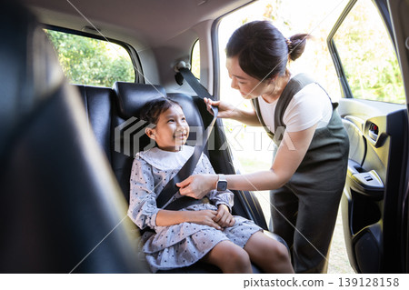 Asian mother fastening seat belt for daughter in car back seat Asian mother fastening seat belt for daughter in car back seat 139128158