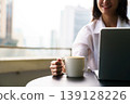 Woman enjoying remote work with laptop and coffee in city 139128226