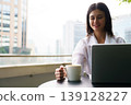 Woman enjoying remote work with laptop and coffee in city 139128227
