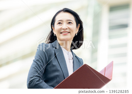 Business woman smiling while holding a notebook Business woman smiling while holding a notebook 139128285