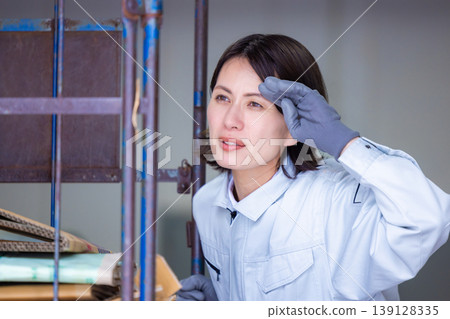 A woman carrying a cardboard cart in a warehouse. 139128335