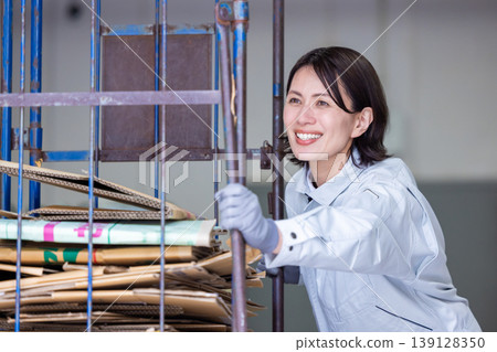 A woman carrying a cardboard cart in a warehouse. A woman carrying a cardboard cart in a warehouse. 139128350