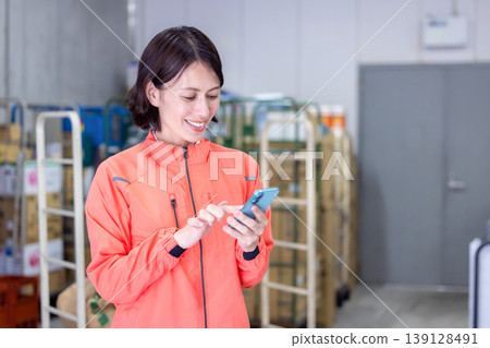 Warehouse - Woman looking at her smartphone 139128491