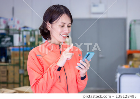 Warehouse - Woman looking at her smartphone Warehouse - Woman looking at her smartphone 139128493
