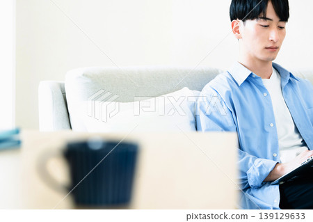 A man who uses a personal computer in the living room A man who uses a personal computer in the living room 139129633