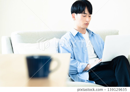 A man who uses a personal computer in the living room A man who uses a personal computer in the living room 139129635