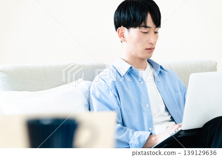 A man who uses a personal computer in the living room A man who uses a personal computer in the living room 139129636