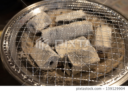 烤肉店裡準備的漂亮的炭烤爐和網子。 烤肉店裡準備的漂亮的炭烤爐和網子。 139129904