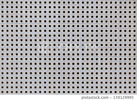 A gray exterior wall background with square holes spaced at equal intervals. A gray exterior wall background with square holes spaced at equal intervals. 139129995