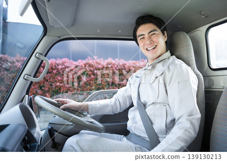 一位微笑的司機正駕駛車輛,目光直視鏡頭。此照片適用於卡車司機及其他從事貨物運輸的駕駛員。 一位微笑的司機正駕駛車輛,目光直視鏡頭。此照片適用於卡車司機及其他從事貨物運輸的駕駛員。 139130213