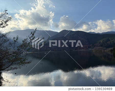湖畔風光，陽光照亮山脈和雲朵，冬日湖面平靜，神秘的自然背景，留白空間 139130469
