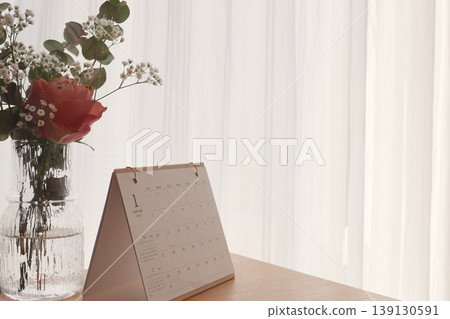 窗邊放著一本台歷，花瓶裡插著花。 139130591