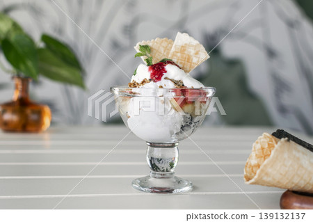 gelato ice cream and mixed fruit sundae dessert in glass cup on outdoor cafe white table 139132137