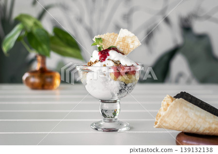 gelato ice cream and mixed fruit sundae dessert in glass cup on outdoor cafe white table 139132138