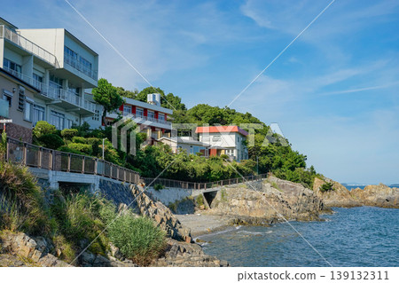 A seaside house with white walls that stands out against the blue sky and sea. 139132311