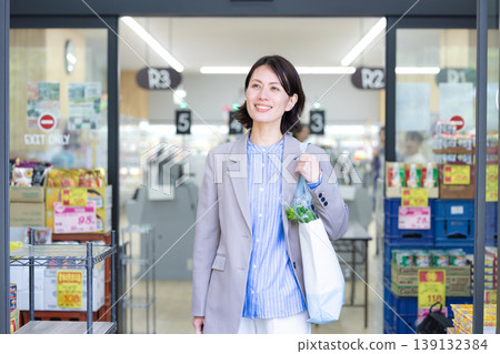 一位剛在超市購物完的女士從店裡走了出來。 139132384