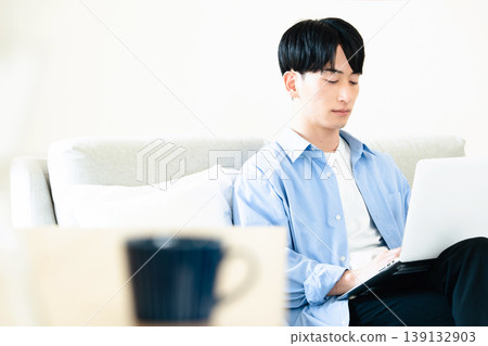A man who uses a personal computer in the living room A man who uses a personal computer in the living room 139132903