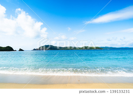 White waves lapping against the sandy shore of Yadori Beach and the scenery of the remote island. White waves lapping against the sandy shore of Yadori Beach and the scenery of the remote island. 139133231
