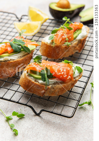 Salmon avocado toasts with microgreens and sesame seeds 139133363