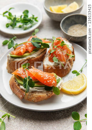 Salmon avocado toasts with microgreens and lemon Salmon avocado toasts with microgreens and lemon 139133425