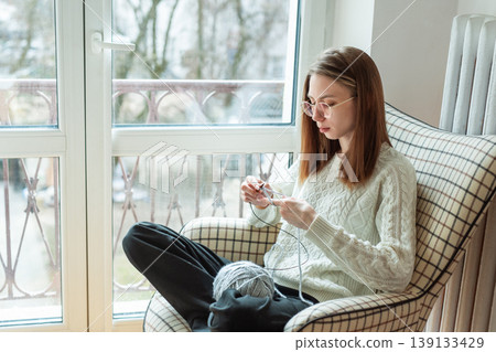 Woman knitting new sweater with gray yarn at home Woman knitting new sweater with gray yarn at home 139133429