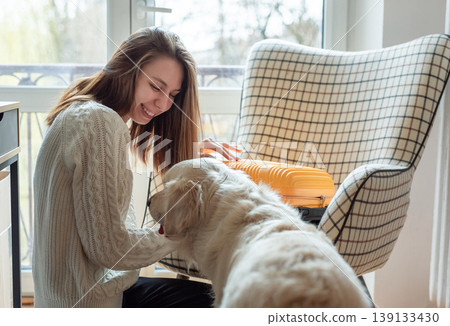 Woman petting happy golden retriever dog preparing for travel 139133430