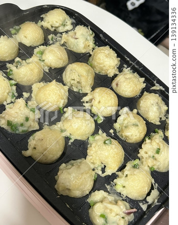 Takoyaki, a popular Japanese street food, are crispy round dough balls filled with octopus, tempura bits, and pickled ginger, topped with takoyaki sauce, bonito flakes, and aonori. Takoyaki, a popular Japanese street food, are crispy round dough balls filled with octopus, tempura bits, and pickled ginger, topped with takoyaki sauce, bonito flakes, and aonori. 139134336