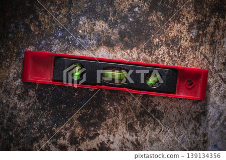 Red professional spirit level tool on rustic industrial background. 139134356