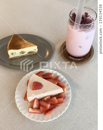 A delightful assortment of desserts displayed in a cozy cafe setting, featuring cakes, pastries, and sweet treats on elegant plates, creating a warm and inviting atmosphere. 139134556