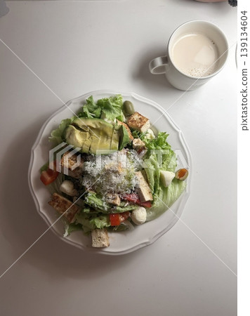 Fresh salad with a mix of crisp leafy greens, sliced vegetables, and colorful ingredients, tossed together to create a healthy, vibrant, and refreshing dish full of natural flavors 139134604