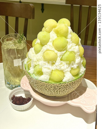 Refreshing melon bingsu with fluffy shaved ice topped with sweet, juicy melon balls, offering a perfect combination of cool, fruity, and creamy flavors in every delightful summer bite. Refreshing melon bingsu with fluffy shaved ice topped with sweet, juicy melon balls, offering a perfect combination of cool, fruity, and creamy flavors in every delightful summer bite. 139134625