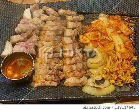Grilled samgyeopsal, thick slices of pork belly with a perfect balance of crispy edges and tender meat. Served with lettuce, garlic, and dipping sauces for a classic Korean barbecue experience. Grilled samgyeopsal, thick slices of pork belly with a perfect balance of crispy edges and tender meat. Served with lettuce, garlic, and dipping sauces for a classic Korean barbecue experience. 139134643
