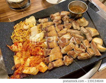 Grilled samgyeopsal, thick slices of pork belly with a perfect balance of crispy edges and tender meat. Served with lettuce, garlic, and dipping sauces for a classic Korean barbecue experience. Grilled samgyeopsal, thick slices of pork belly with a perfect balance of crispy edges and tender meat. Served with lettuce, garlic, and dipping sauces for a classic Korean barbecue experience. 139134644