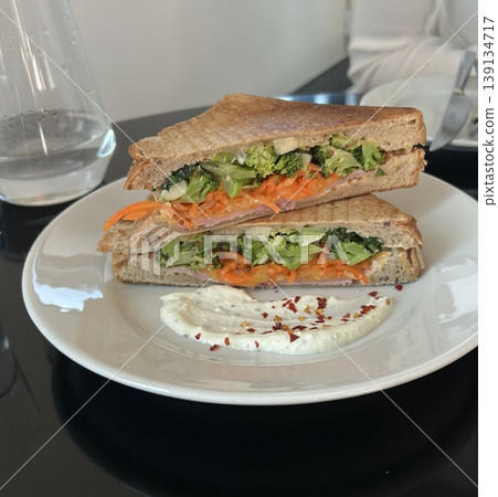 Delicious sandwich filled with fresh ingredients like crisp vegetables, tender meats, and savory spreads, all between two slices of soft bread. Perfect for a quick and satisfying meal. Delicious sandwich filled with fresh ingredients like crisp vegetables, tender meats, and savory spreads, all between two slices of soft bread. Perfect for a quick and satisfying meal. 139134717