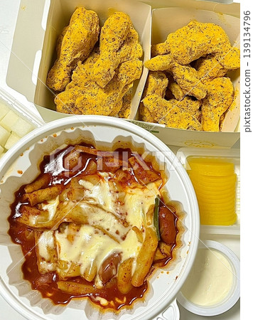 Spicy yeoptteok paired with crispy Korean fried chicken, combining fiery rice cakes and savory crunch for an irresistible duo that’s bold, satisfying, and full of Korean street food flavor. 139134796