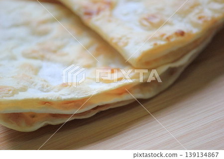 Side view close up of crispy stacked homemade flatbread resting on a smooth wooden board Side view close up of crispy stacked homemade flatbread resting on a smooth wooden board 139134867