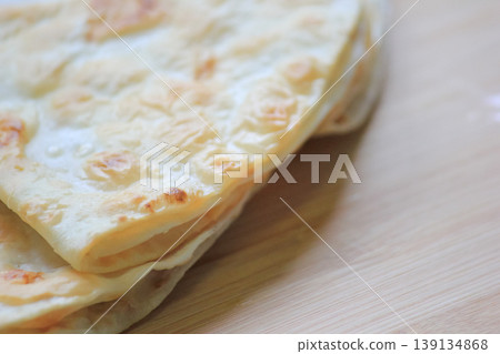 Side view close up of crispy stacked homemade flatbread resting on a smooth wooden board Side view close up of crispy stacked homemade flatbread resting on a smooth wooden board 139134868